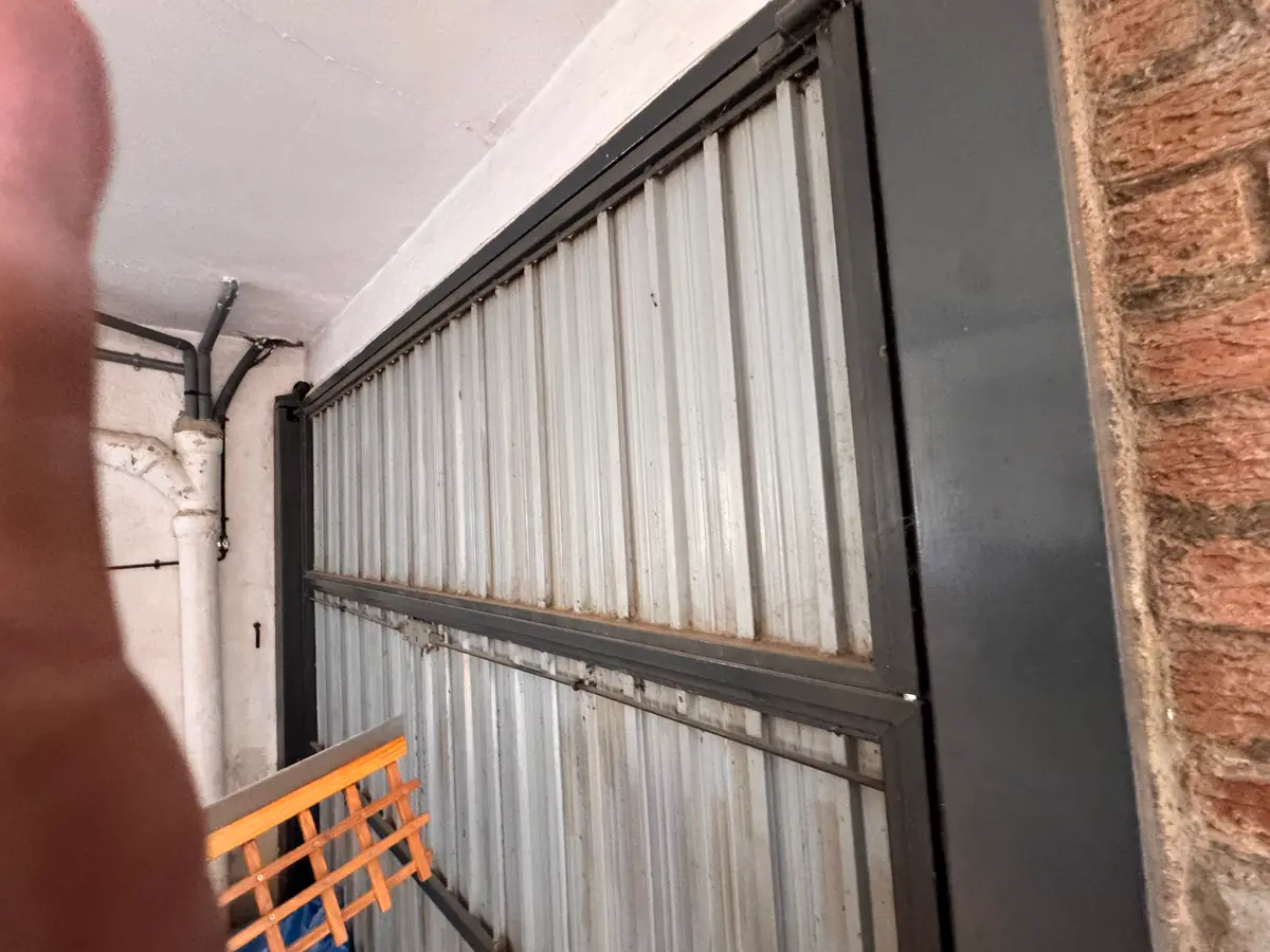 Porta basculant antiga de xapa d’un garatge, vista des de dins abans de substituir-la